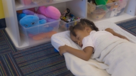 A toddler naps on her nap pad.