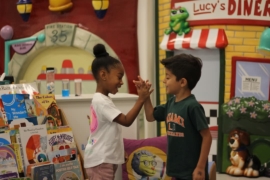 A boy and girl give each other a high five.