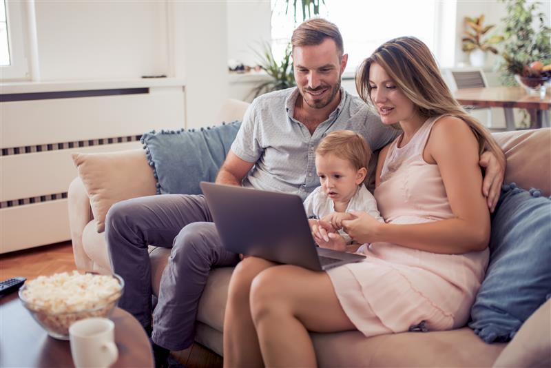 Mother and Father research preschools on a computer with their child between them.