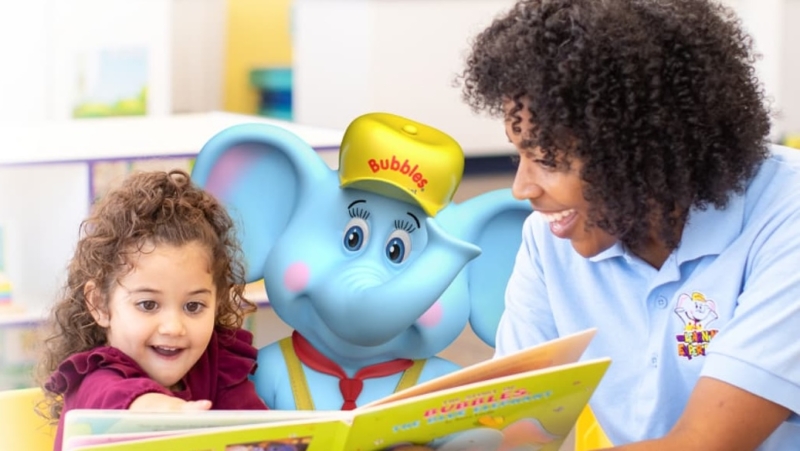 Bubbles reads with a teacher and child.